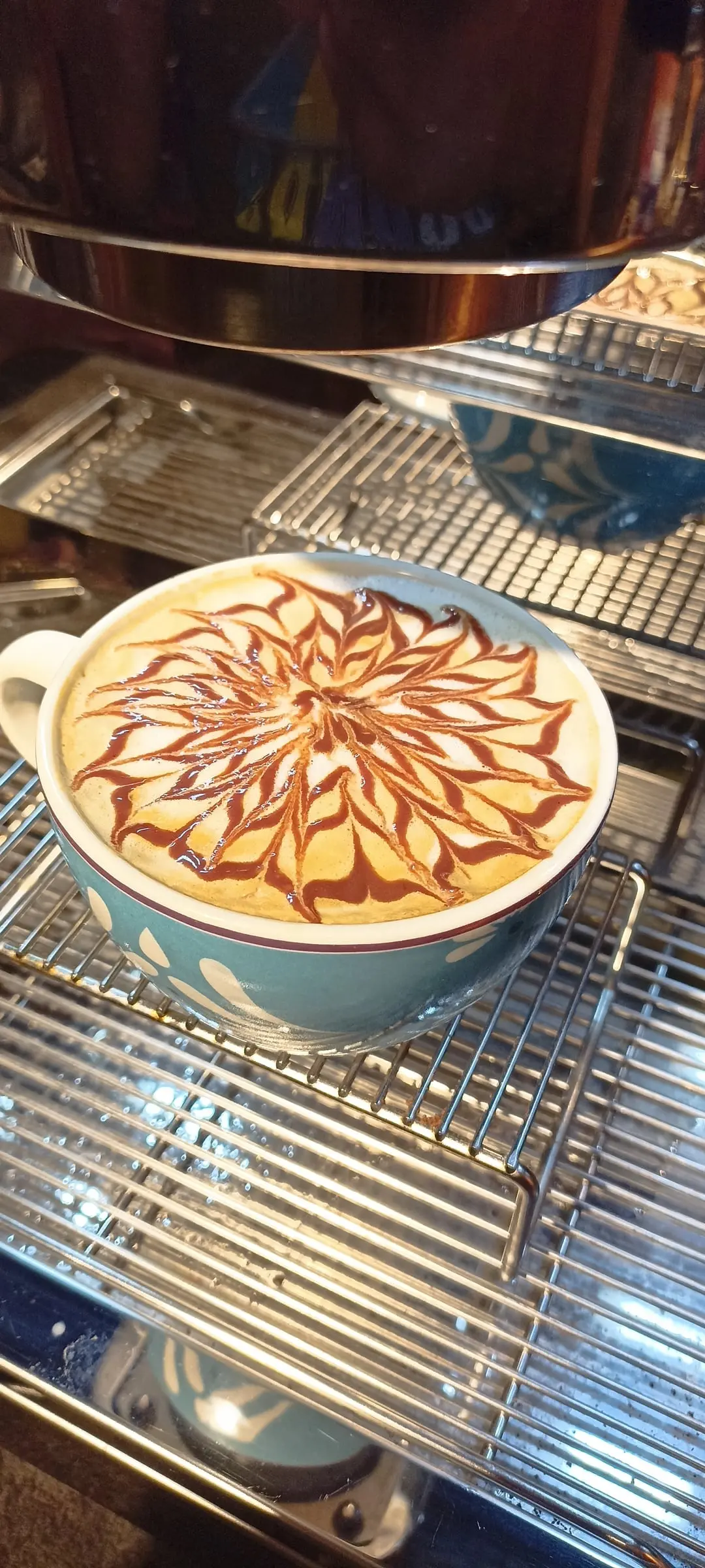 Capuchino con arte latte recién servido sobre la máquina de espresso de Café EKA