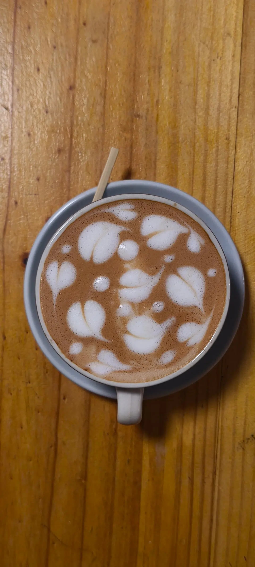 Latte con arte de hojas sobre una mesa de madera en Café EKA