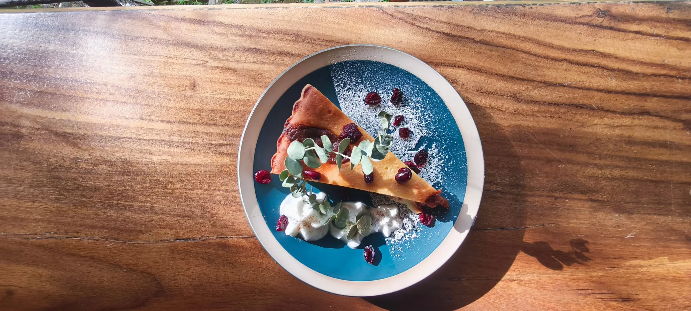 Postre en plato azul con frutos rojos y crema